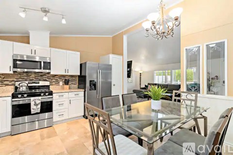 A modern kitchen with a glass dining table and chairs.
