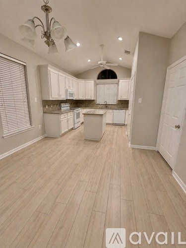 A kitchen with white cabinets and a wooden floor.