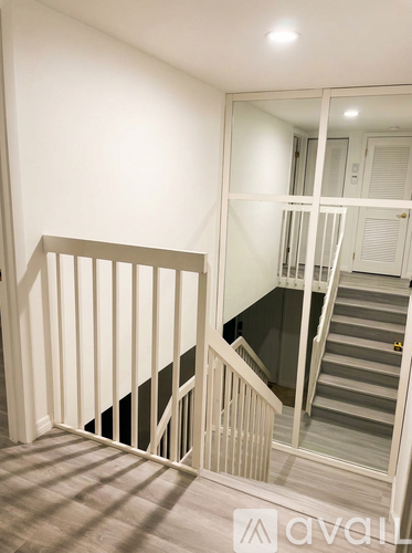 A staircase with a white railing and a mirror on the wall.