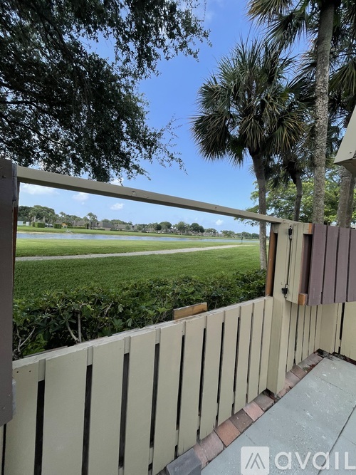 A balcony with a view of a green field and trees.