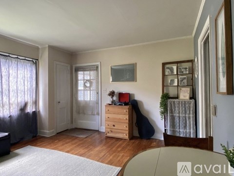 A room with a wooden floor and a white rug in the foreground.