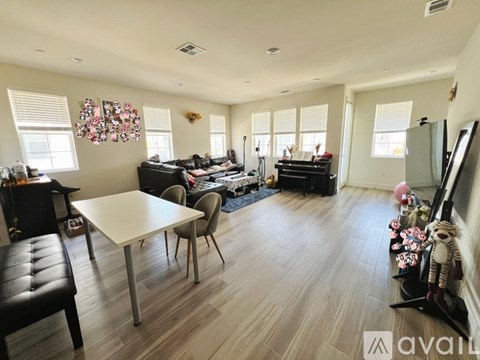 A living room with a white table and chairs, a black couch, and a TV.
