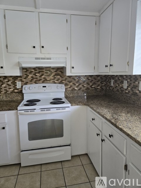 A kitchen with white cabinets and a white stove top oven.