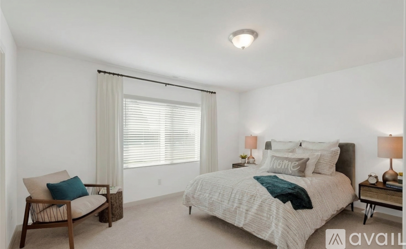 A bedroom with a bed, chair, and window.