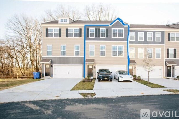 A two-story building with a blue trim and a carport with two cars parked in front.