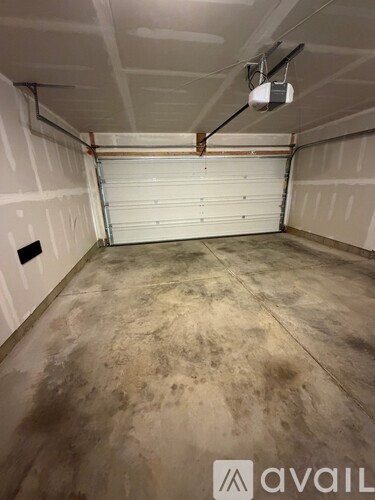A garage with a white roller shutter door and a concrete floor.