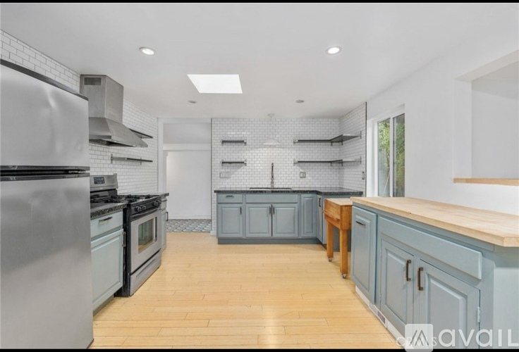 A kitchen with a stainless steel refrigerator and wooden flooring.