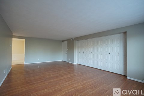 A room with wooden floors and a white wall with a door.
