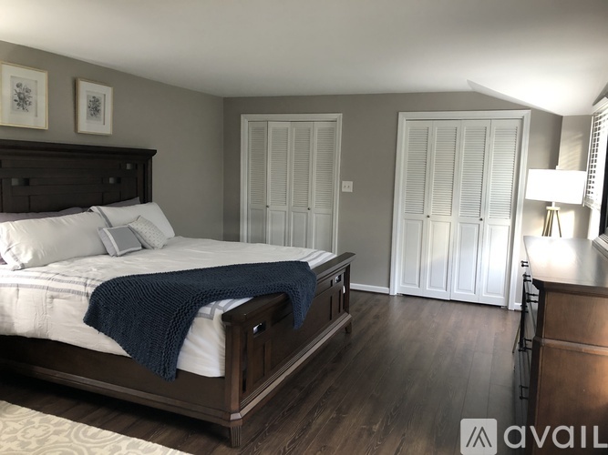 A bedroom with a large bed and a wooden dresser.