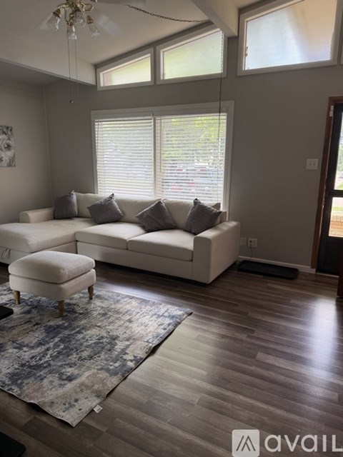 A living room with a white couch and a rug.