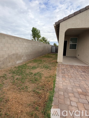 A backyard with a brick walkway and a wall.