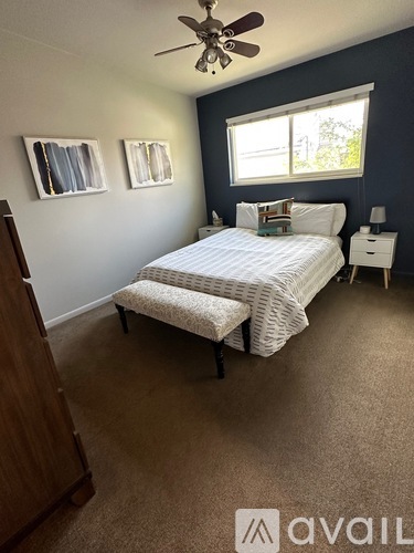 A bedroom with a bed, nightstand, and a ceiling fan.