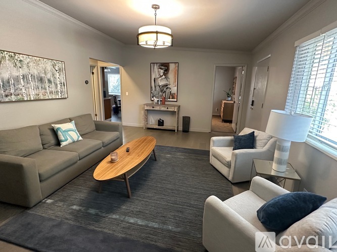 A living room with a grey sofa, a wooden coffee table, and a white chair.