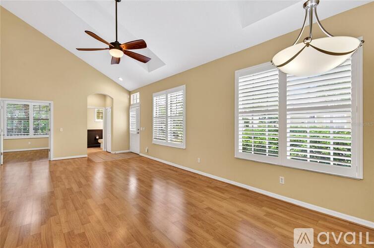 A spacious room with a ceiling fan and a hanging light fixture.