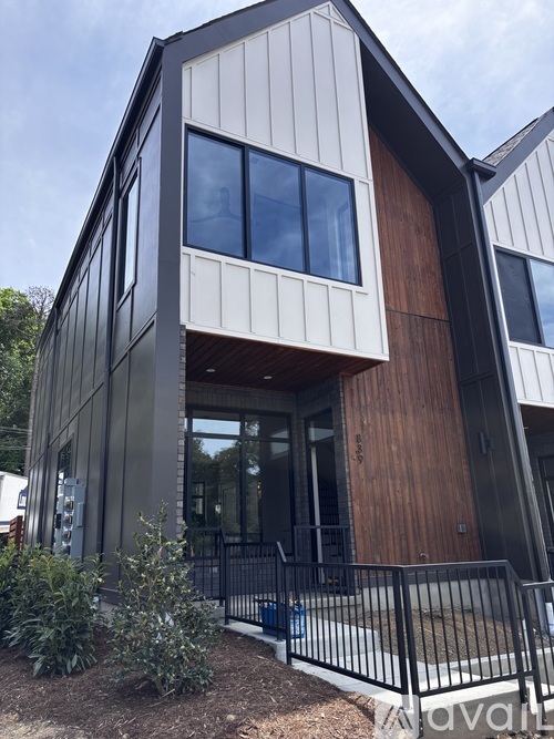 A modern house with a black and white exterior and a wooden door.