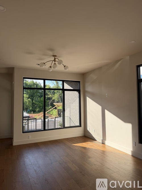 A room with wooden floors and a large window overlooking a residential area.