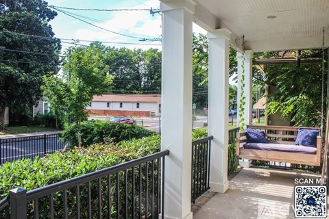 A balcony with a black railing and a white column.