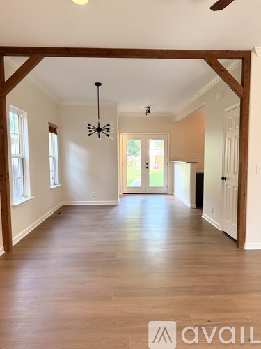 A spacious room with wooden floors and white walls.