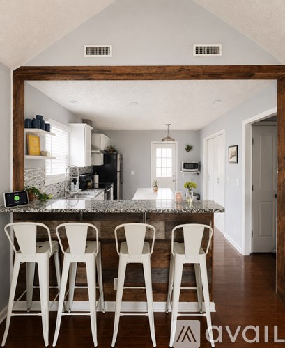 A kitchen with a bar area and white chairs.