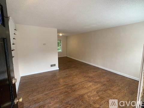 A room with wooden flooring and white walls.