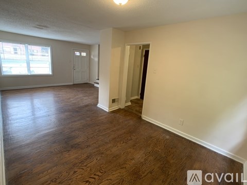 A room with wooden floors and white walls, with a door on the right side.