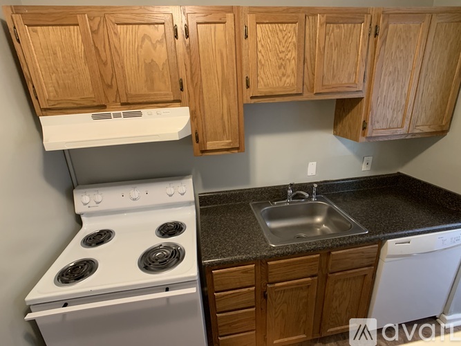 A kitchen with wooden cabinets and a white stove top oven.