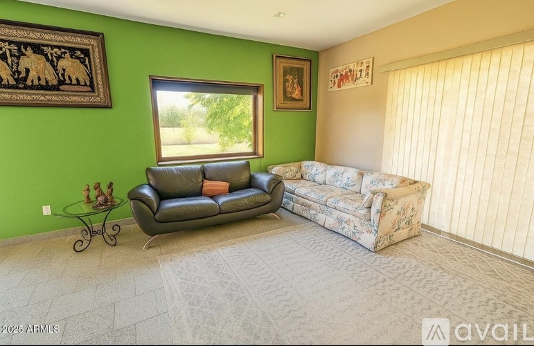 A living room with a green wall and a black leather sofa.