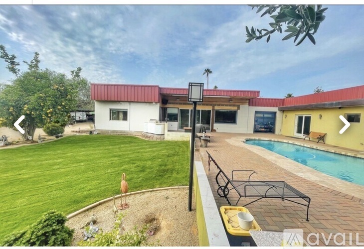 A house with a red roof and a pool in the backyard.