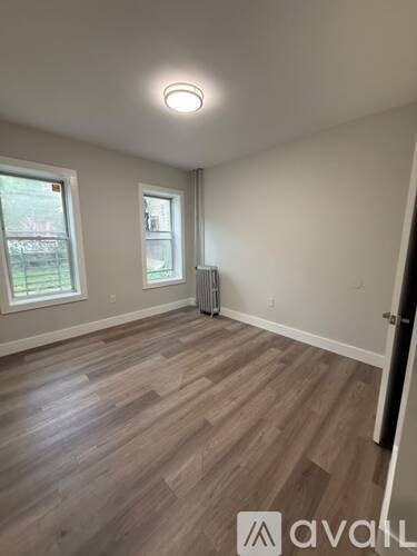 A room with wooden flooring and a window with blinds.