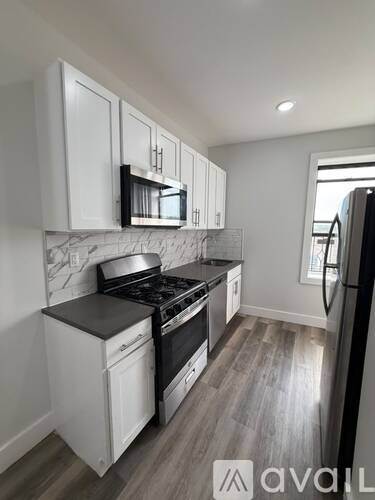 A kitchen with white cabinets and a black stove top oven.