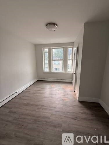 A room with a window and a wooden floor.