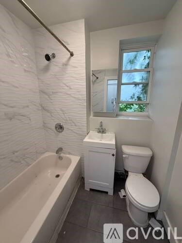 A white bathroom with a tub, toilet and sink.