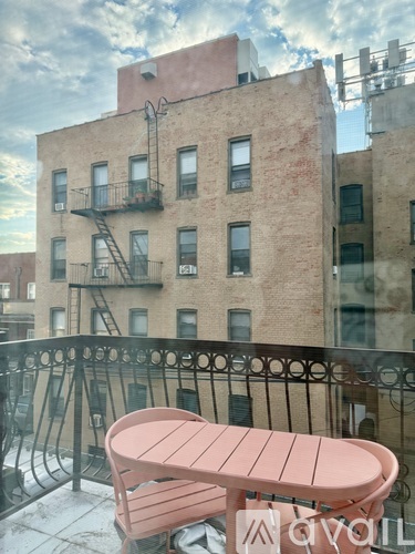 A pink table and chairs on a balcony with a building in the background.