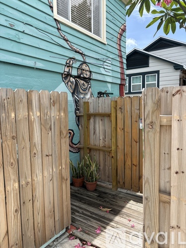 A wooden fence with a gate and a plant on the ground.