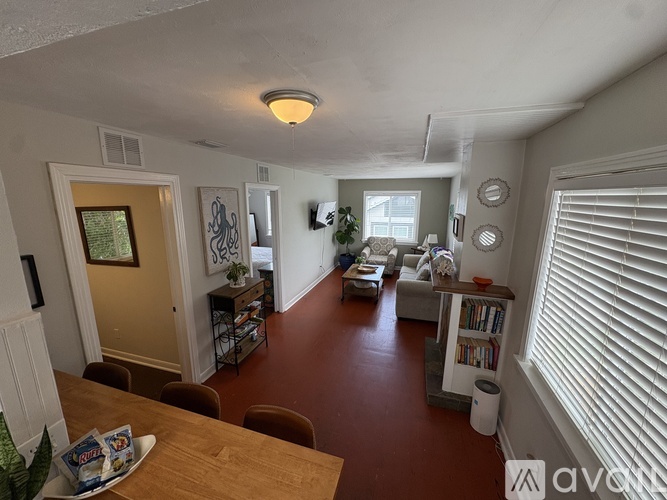 A living room with a brown floor and white walls.
