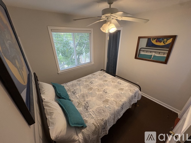 A bedroom with a bed, a ceiling fan, and a window.