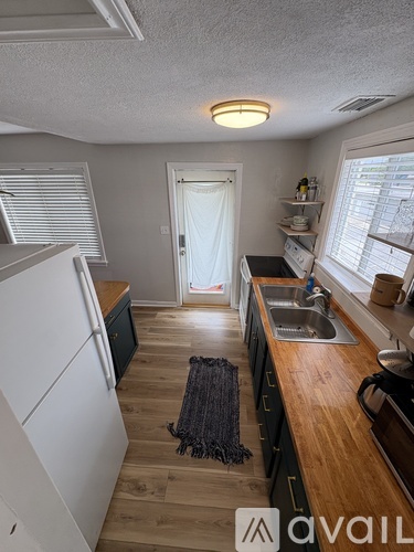 A kitchen with a white refrigerator and wooden countertops.