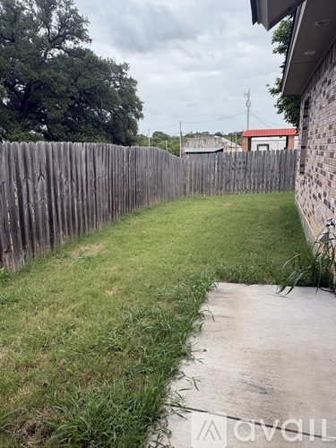 A backyard with a wooden fence and a concrete path.