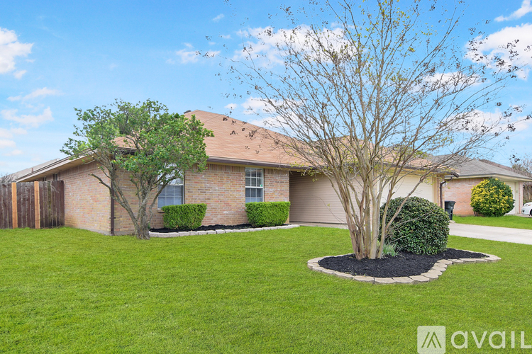 A house with a brown roof and a tree in the front yard.