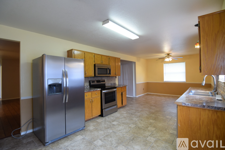 A kitchen with a refrigerator, microwave, oven, sink and cabinets.