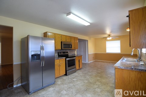 A kitchen with a refrigerator, microwave, oven, sink and cabinets.