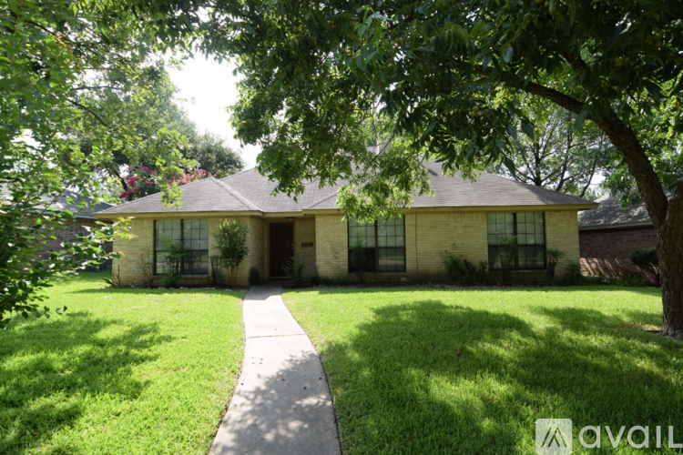 A house with a green lawn and a tree in front of it.