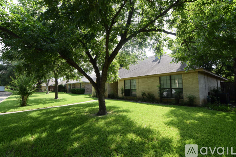 A tree in a yard with a house in the background.