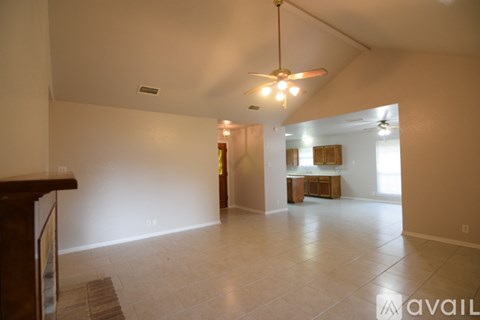 A spacious living room with a ceiling fan and a rug on the floor.