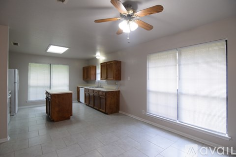 A kitchen with wooden cabinets and a ceiling fan.