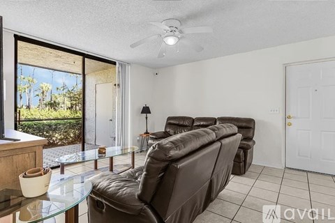 A living room with a brown leather couch and a glass table.