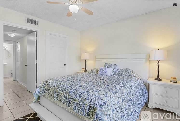 A bedroom with a bed, two lamps, and a ceiling fan.