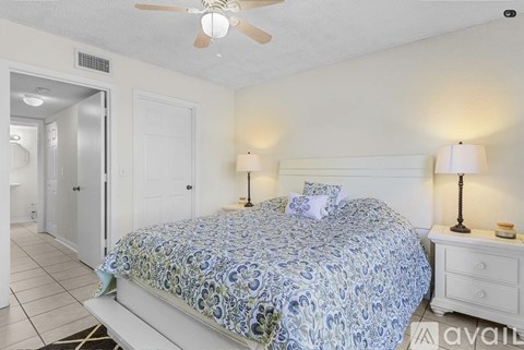 A bedroom with a bed, two lamps, and a ceiling fan.