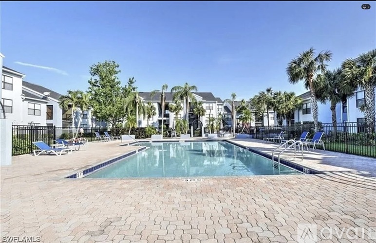 A swimming pool surrounded by palm trees and lounge chairs.