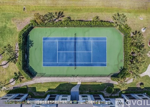A tennis court surrounded by greenery and buildings.
